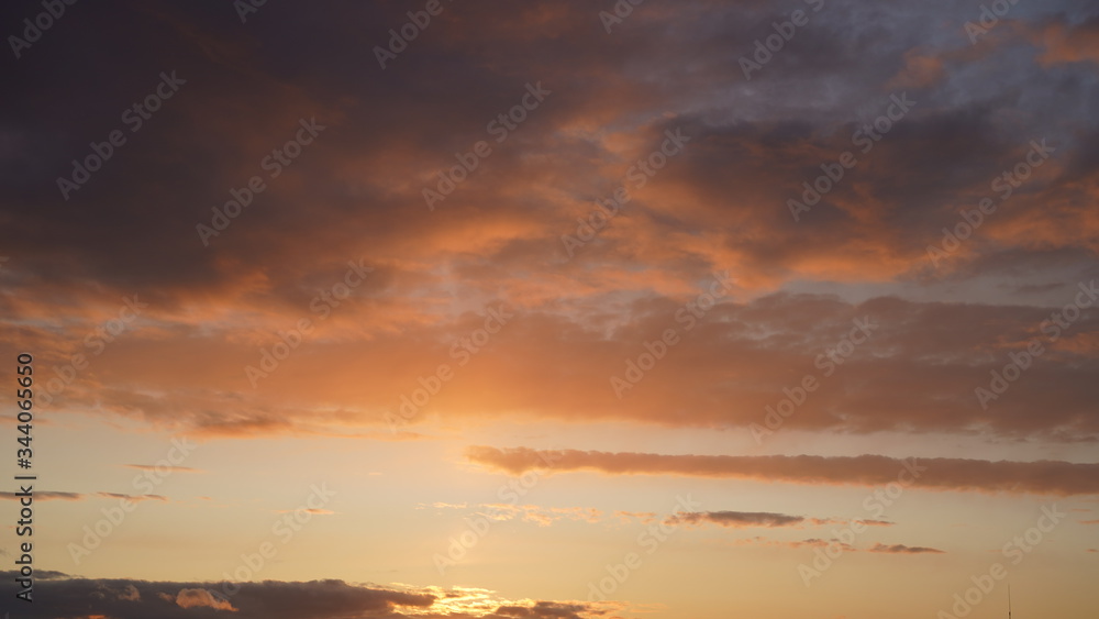 Beautiful evening blue sky at sunset with flaming bright light clouds. A warm summer evening at sunset. Beautiful evening blue sky at sunset with flaming bright light clouds. A warm summer evening at sunset.