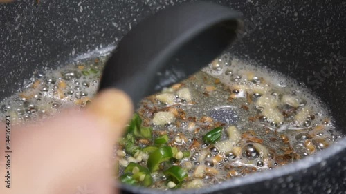 Frying Onions with green chilies, garlic, ginger and cumin seeds to make Tadka to make of spicy Indian lentils called Daal tadka. A 4K video resolution.