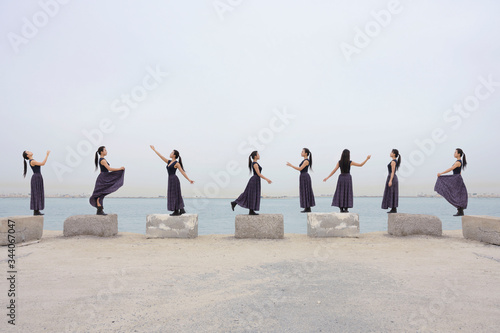 Same woman cloning standing on the bricks posing on the beach over white sky background. photo