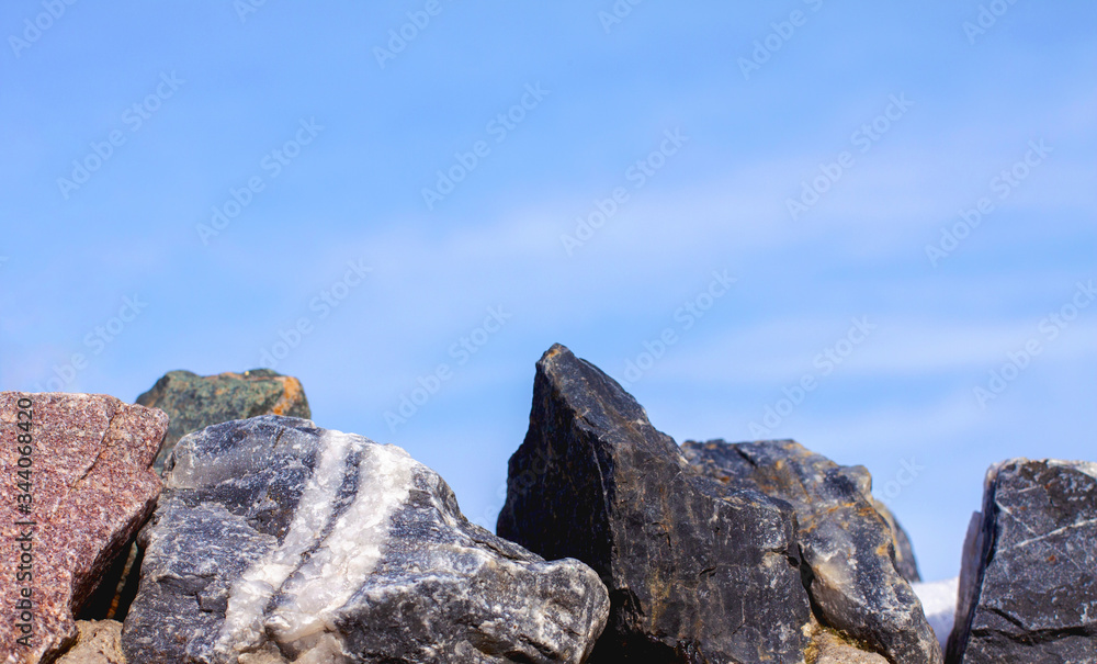 Large stones close-up at the bottom of the frame against a blue cloudy sky Large stones close-up at the bottom of the frame against a blue cloudy sky