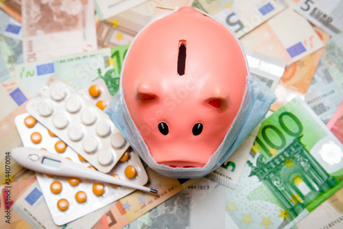 piggy bank in a mask on a background of European currency.The concept of coronavrius epidemic
