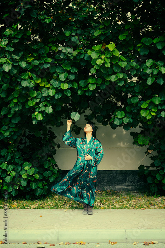 Woman wearing dress holding leaves in green garden background