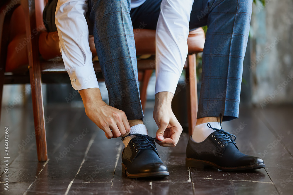 Close-up young man tying elegant shoes indoors Close-up young man tying elegant shoes indoors