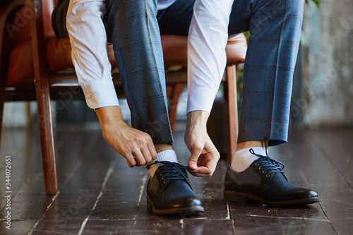 Close-up young man tying elegant shoes indoors