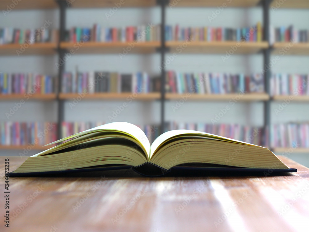 book open on wood table with bookshelf backgrund. book open on wood table with bookshelf backgrund.