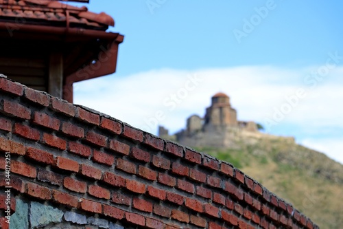 Red Old brick Wall. Church on the background blurred. The Mtskheta Church of Jvari 