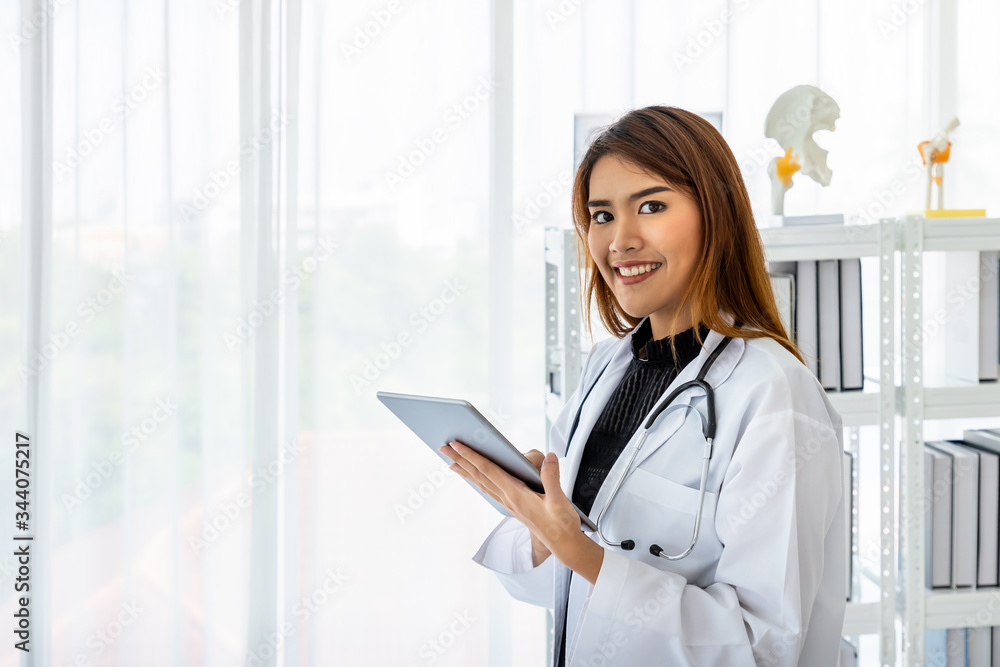 Asian female medical doctor using digital tablet in office clinic hospital with smiling and looking at camera Asian female medical doctor using digital tablet in office clinic hospital with smiling and looking at camera