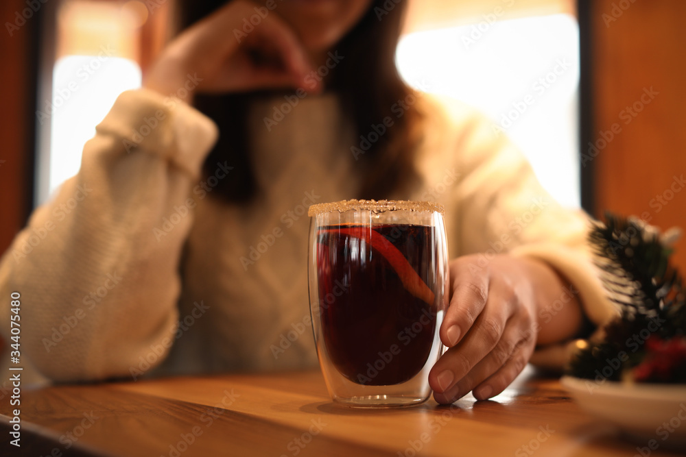 Woman with tasty mulled wine at table in cafe, closeup