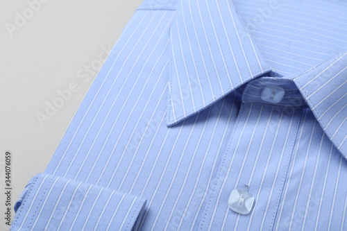 Stylish light blue shirt on white background, closeup. Dry-cleaning service