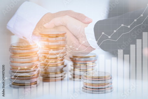 Canvas Print Successful cooperative, teamwork, and joint venture concept; double exposure of handshake and coins stack, with growing trend graph
