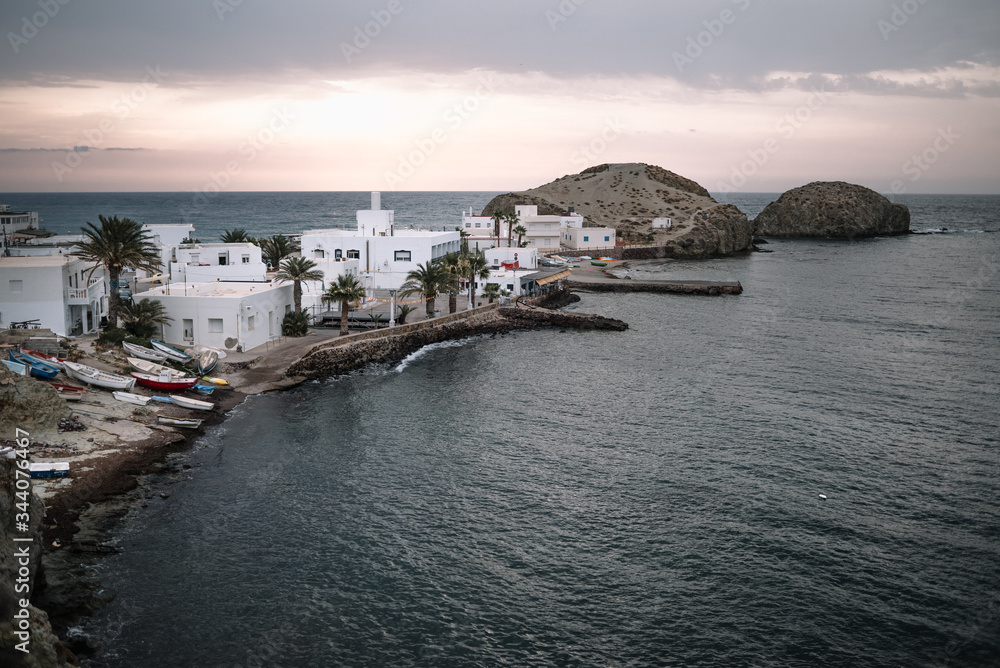 Fototapeta premium La Isleta del Moro, a small town by the sea at dawn with boats moored out of the water, typical white houses with undamaged land and palm trees.