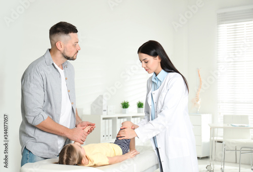 Professional orthopedist examining little patient's leg in clinic