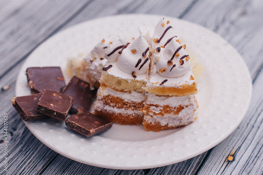 on a white plate chocolate with nuts and a piece of cake with white cream on a white plate chocolate with nuts and a piece of cake with white cream