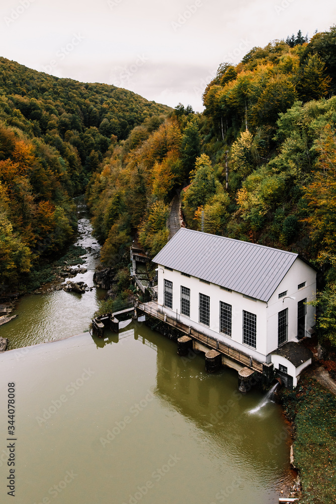 Small house next to a backwater river inside a forest in autumn