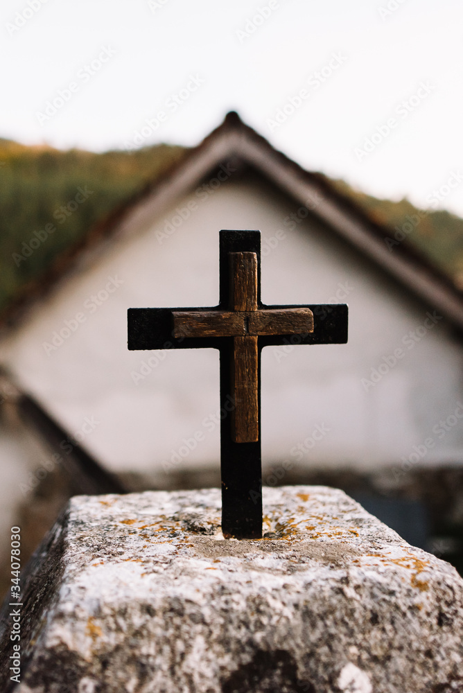 Wooden Christian cross with unfocused rural background.