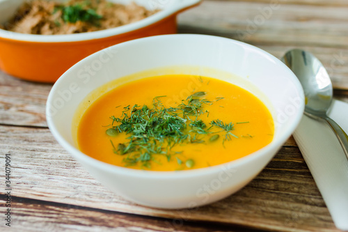 Traditional pumpkin soup with seeds, dill on a wooden table.