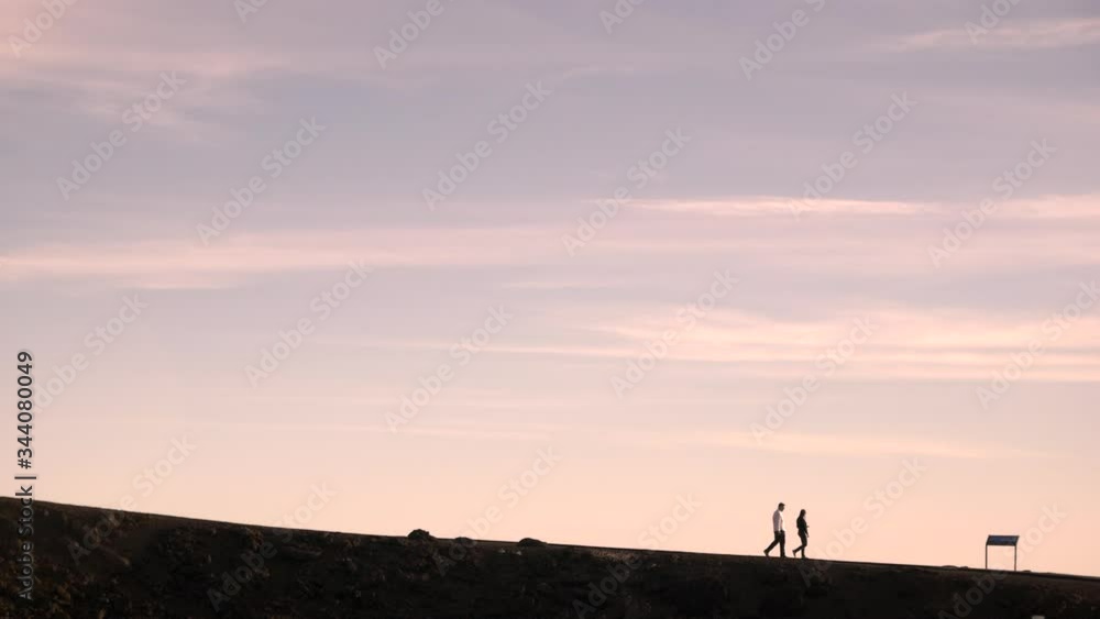Silhouette of day hikers walking along a distant barren ridgeline trail during golden hour on Haleakala, Red Hill Silhouette of day hikers walking along a distant barren ridgeline trail during golden hour on Haleakala, Red Hill