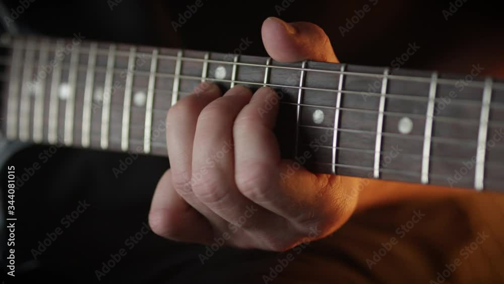 Guitar player practices rock style solo on electric guitar in studio, close up. Guitar player practices rock style solo on electric guitar in studio, close up.