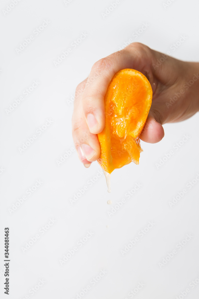 Hand of woman squeezing orange for juice isolated on white background. Cropped shot, closeup. Fresh juice or organic food concept Hand of woman squeezing orange for juice isolated on white background. Cropped shot, closeup. Fresh juice or organic food concept