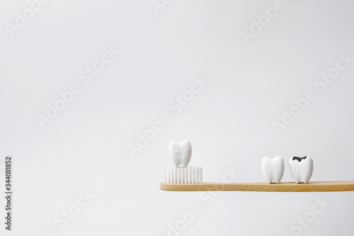 Decayed Tooth and Healthy Tooth on Wooden Brown Toothbrush on White Background  The first step in preventing a dental cavity is to start and keep up with a comprehensive oral hygiene routine.   