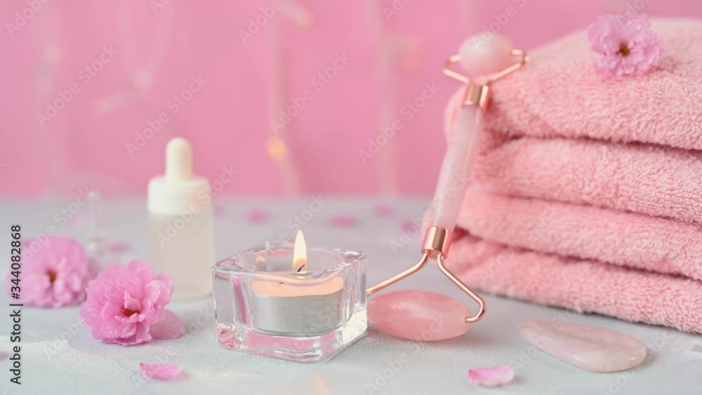 pink jade massager between pastel rose hidebound towels and burning scented candle in bathroom at home close view pink jade massager between pastel rose hidebound towels and burning scented candle in bathroom at home close view