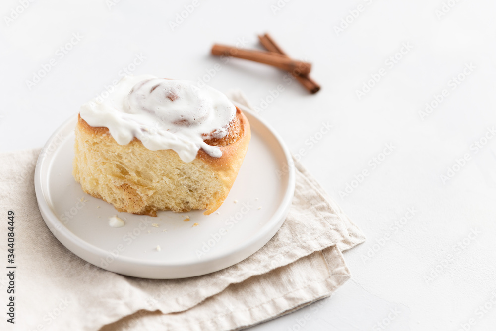 Cinnamon roll or cinnabon with cream sauce on white background. Homemade buns. Bakery menu, recipe, pastry, cook book. Hygge. Copy space, side view