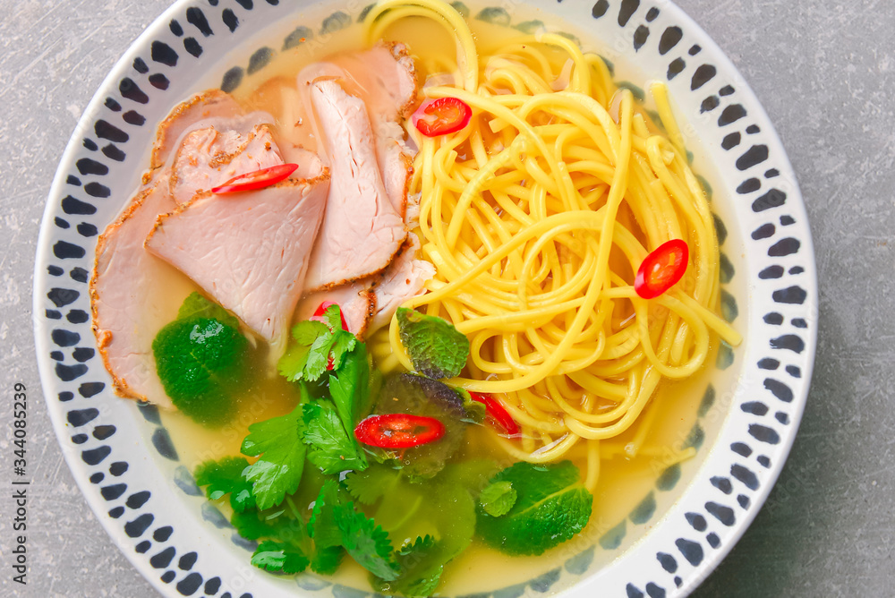 Japanese ramen soup with noodles, beef, egg, fresh parsley and sweet pepper on gray background. Copy space banner. Japanese ramen soup with noodles, beef, egg, fresh parsley and sweet pepper on gray background. Copy space banner.
