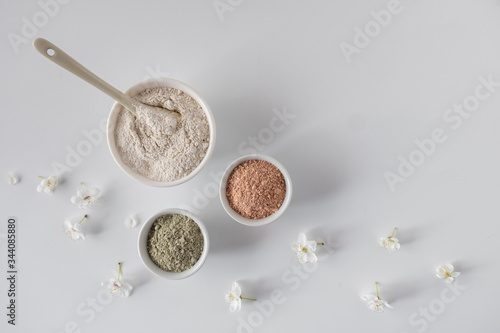 Set of different cosmetic clay mud powders on white background