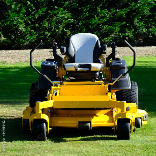 Lawn mower park by green grass field, zero turn Lawn mower.
