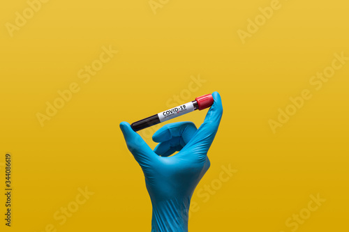 hand in blue rubber glove holding Coronavirus blood sample in test tube for covid-19 analyzing with positive results. laboratory analyzing for testing and invent drug and vaccine for Coronavirus