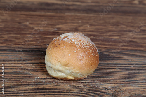 View, closeup of a fresh, homemade bread roll with sprinkles on a wooden, brown, rustic table.