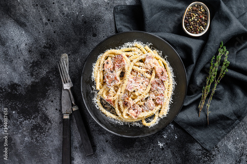 Pasta Carbonara on black plate with parmesan, bucatini. Black background. Top view