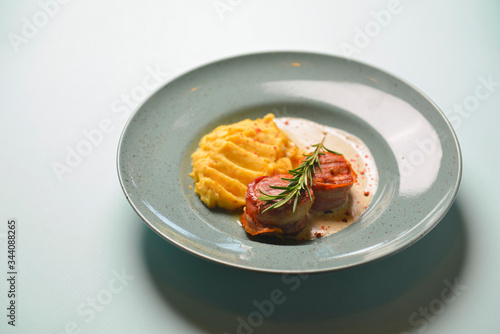 Beef meat pieces with mashed potato, onion gravy and spices. Served on a blue plate over blue mint background.