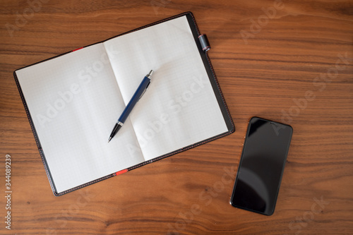 notebook and pen on table with smartphone.