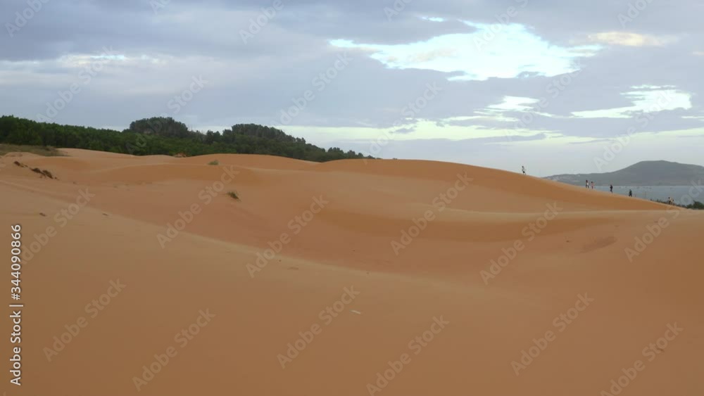 Low angle view of red sloping sand dunes toward trees on sunny day, Vietnam Low angle view of red sloping sand dunes toward trees on sunny day, Vietnam