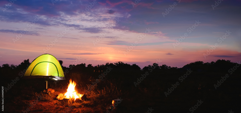 Camping tent near small bonfire in twilight. Banner design
