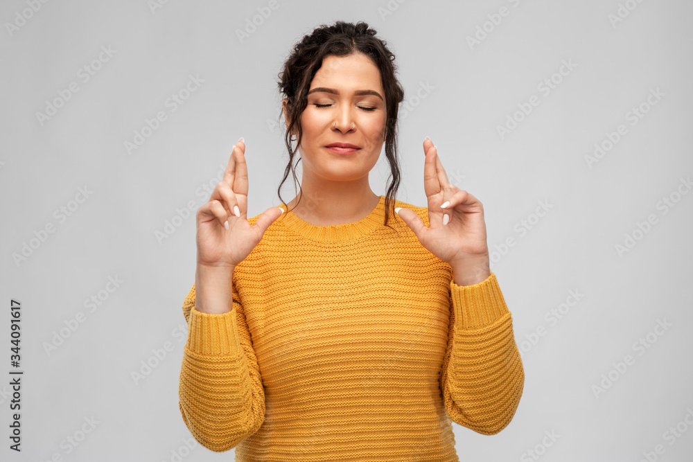 people, gesture and portrait concept - happy young woman with pierced nose holding fingers crossed over grey background people, gesture and portrait concept - happy young woman with pierced nose holding fingers crossed over grey background