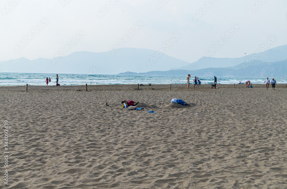 two women lie in the sand against the background of the sea.