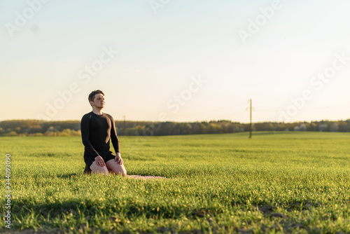 young man doing yoga exercises in the park