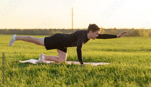 young man doing yoga exercises in green field  © matviy1
