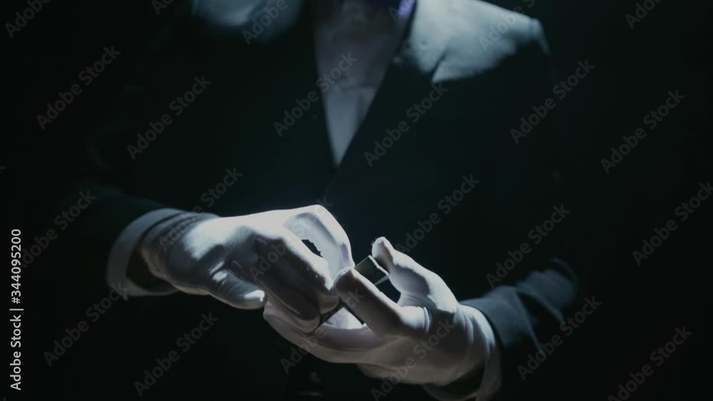 Close-up of a Suited Magician's Hands Performing Sleight of Hand Card Tricks. Cards fly and turn over in the air. Slow Motion. Background is Black.