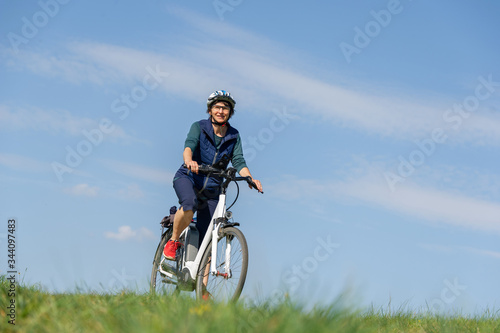 Querfeldein mit dem E-Bike durch den Frühling, Frau genießt Fahrrad fahren in der Natur.