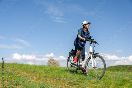 Querfeldein mit dem E-Bike durch den Fr  hling  Frau genie  t Fahrrad fahren in der Natur.