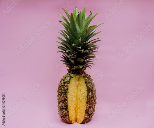 A sexy pineapple cut open in front of a pink background.