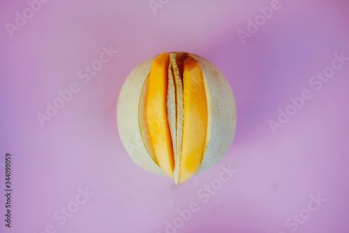 Sliced open melon with yonic fruit assortment over bright colorful background. photo