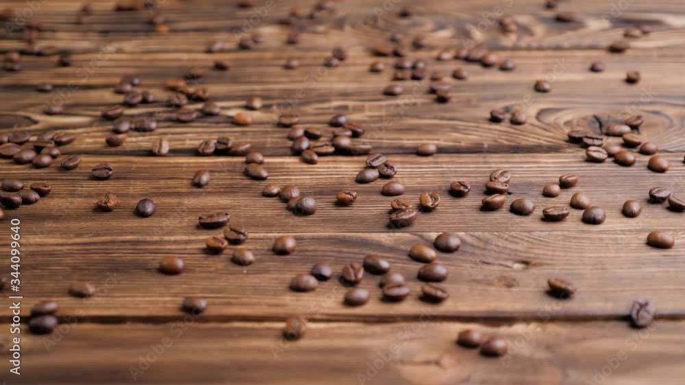 Roasted coffee beans on a wooden table. Cam moves to the left, slow motion. Roasted coffee beans on a wooden table. Cam moves to the left, slow motion.