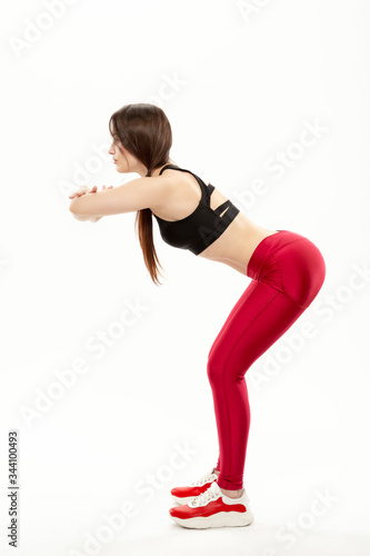 young, slim girl doing sports exercises and warm-up isolated on a white background