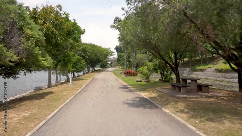 Smooth point of view (POV) footage on a jogging track in a beautiful public park in a sunny day.
