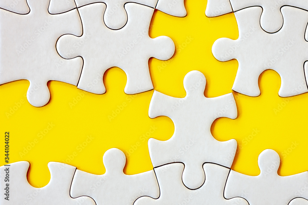 Puzzle pieces on yellow background. White square puzzle pieces grid. Business background. Top view, close up. Puzzle pieces on yellow background. White square puzzle pieces grid. Business background. Top view, close up.