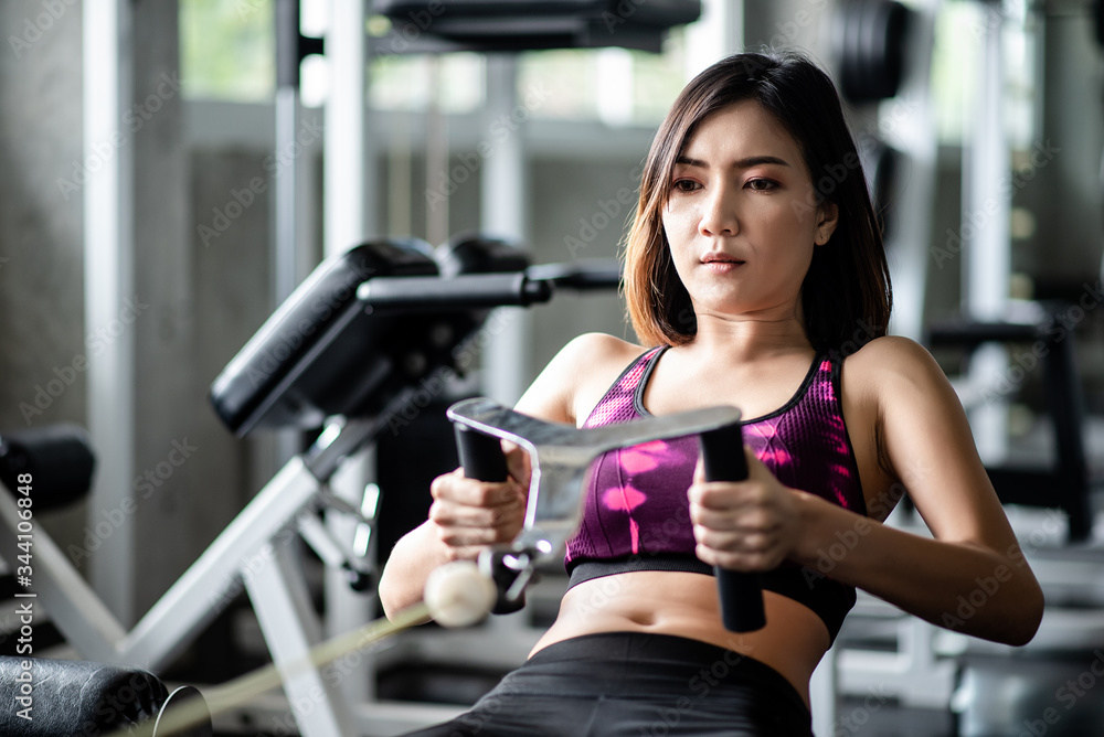 Obraz premium Young healthy woman working out with cable in the gym